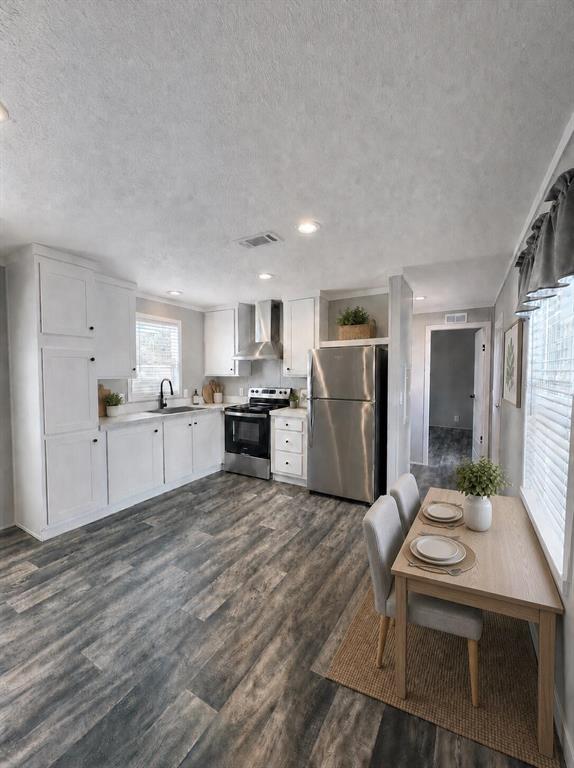 A kitchen features white cabinets, stainless steel appliances, and a small dining table — 6615 BANDURA AVENUE, NEW PORT RICHEY, FL