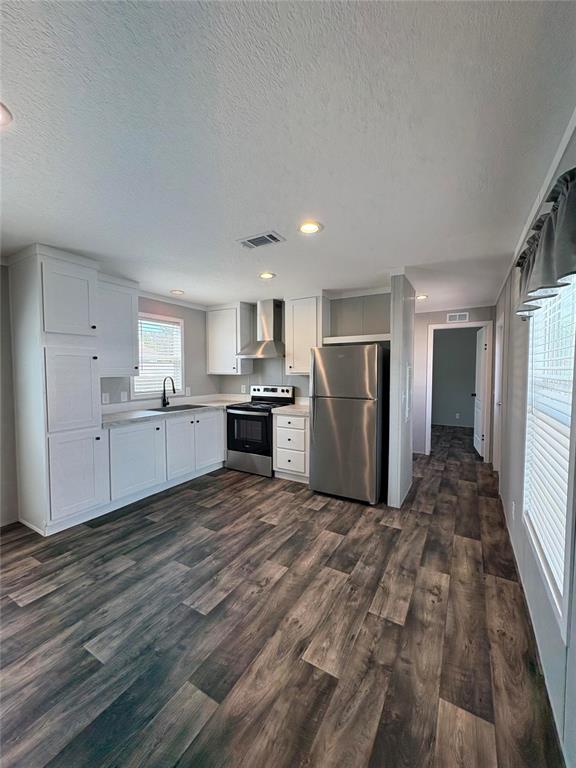 A kitchen features white cabinets, stainless steel appliances, and wood-look flooring — 6615 BANDURA AVENUE, NEW PORT RICHEY, FL