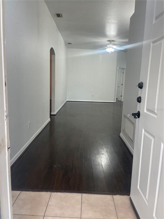 An entryway with tile flooring leads into a living area featuring dark wood-look floors — 5418 FREDERICK LAKE DRIVE, PORT ORANGE, FL