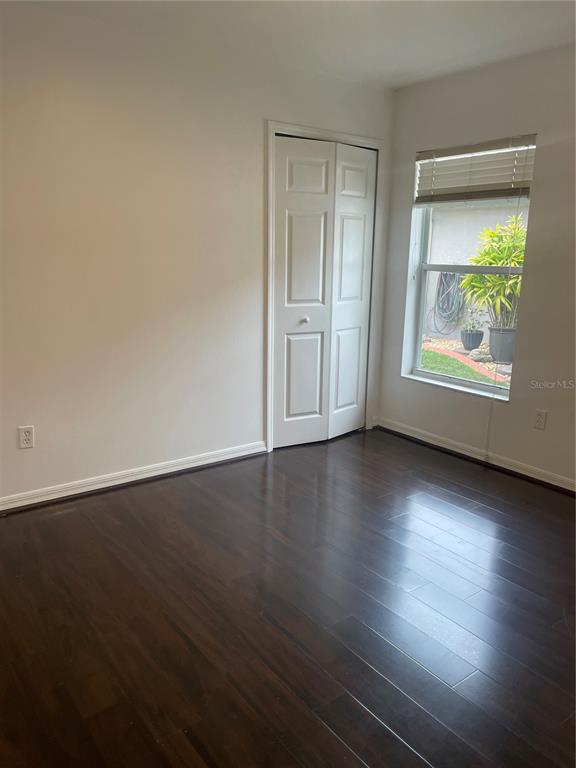 A bedroom with dark wood flooring, white walls, a bi-fold closet, and a window — 5418 FREDERICK LAKE DRIVE, PORT ORANGE, FL