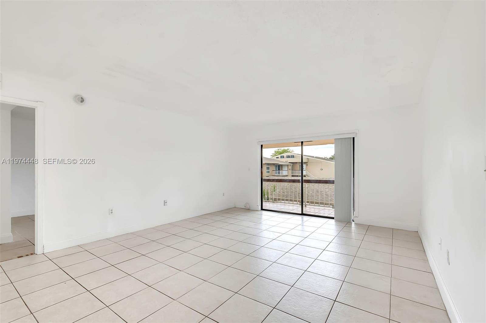 An empty room with white walls, tiled flooring, and a sliding glass door to a balcony — 13787 SW 66th St # 254D, Miami FL 33183, MIAMI, FL