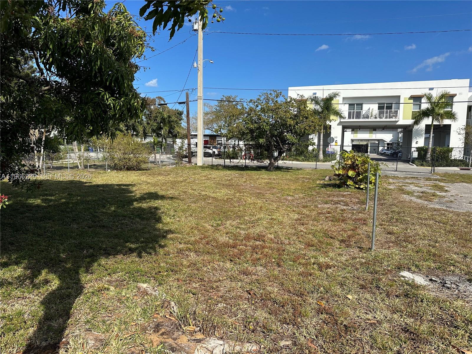 An empty, grassy lot sits in front of a modern white building with a balcony — . NW 2nd Ave, Hallandale Beach FL 33009, HALLANDALE BEACH, FL