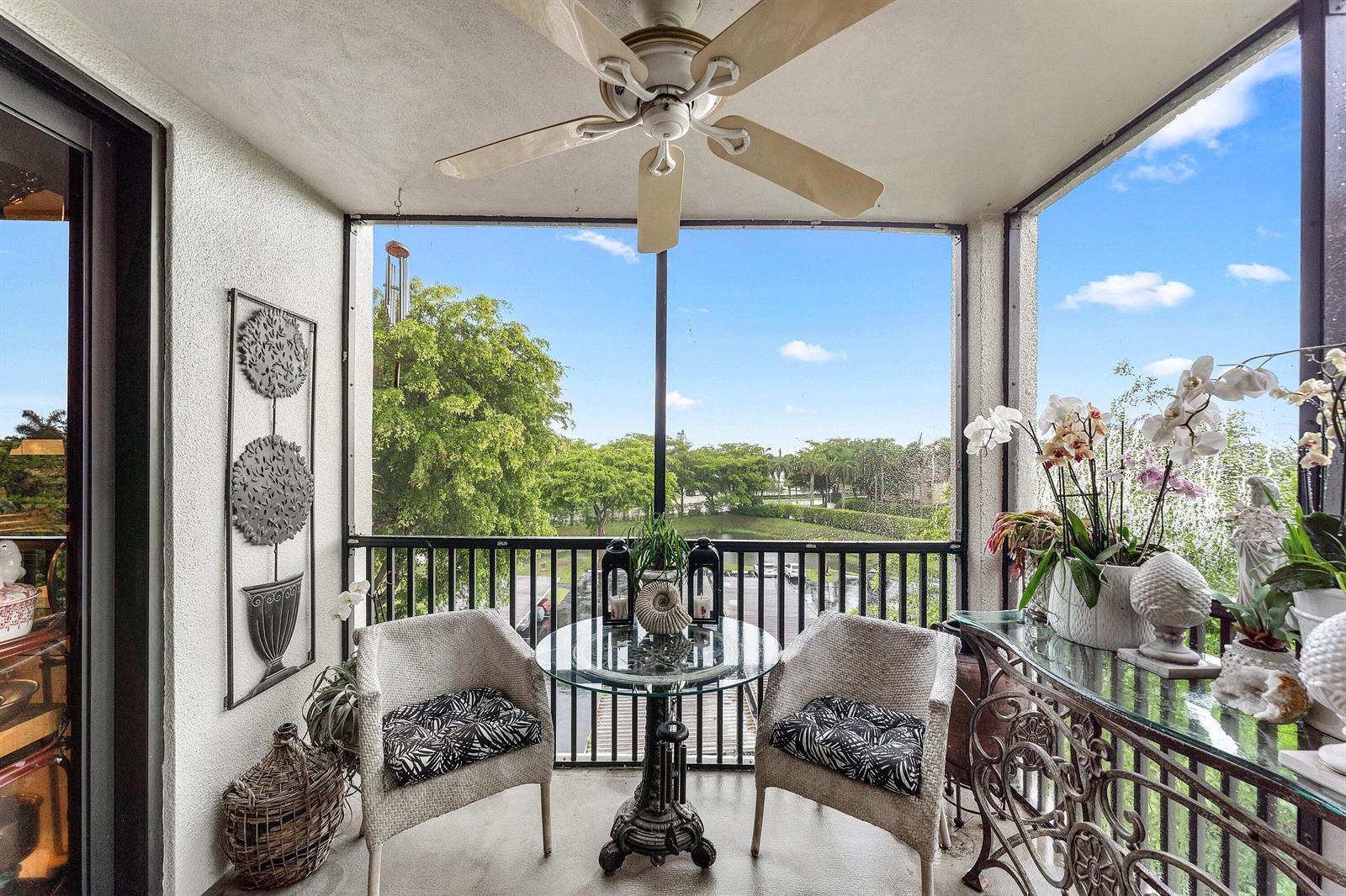 A screened-in balcony features a glass-topped bistro set, two wicker chairs, and a ceiling fan — 5951 Wellesley Park Drive # 507, Boca Raton FL 33433, BOCA RATON, FL