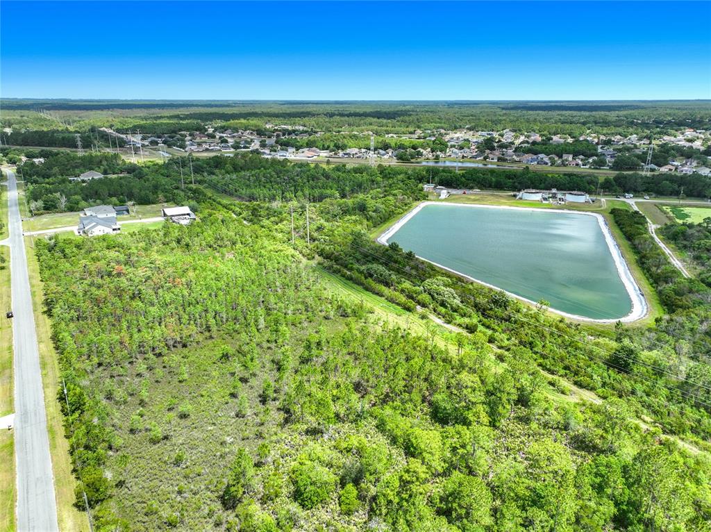 An aerial view shows a wooded lot next to a large pond and residential neighborhood — 00 WEMBLEY AVENUE, ORLANDO, FL