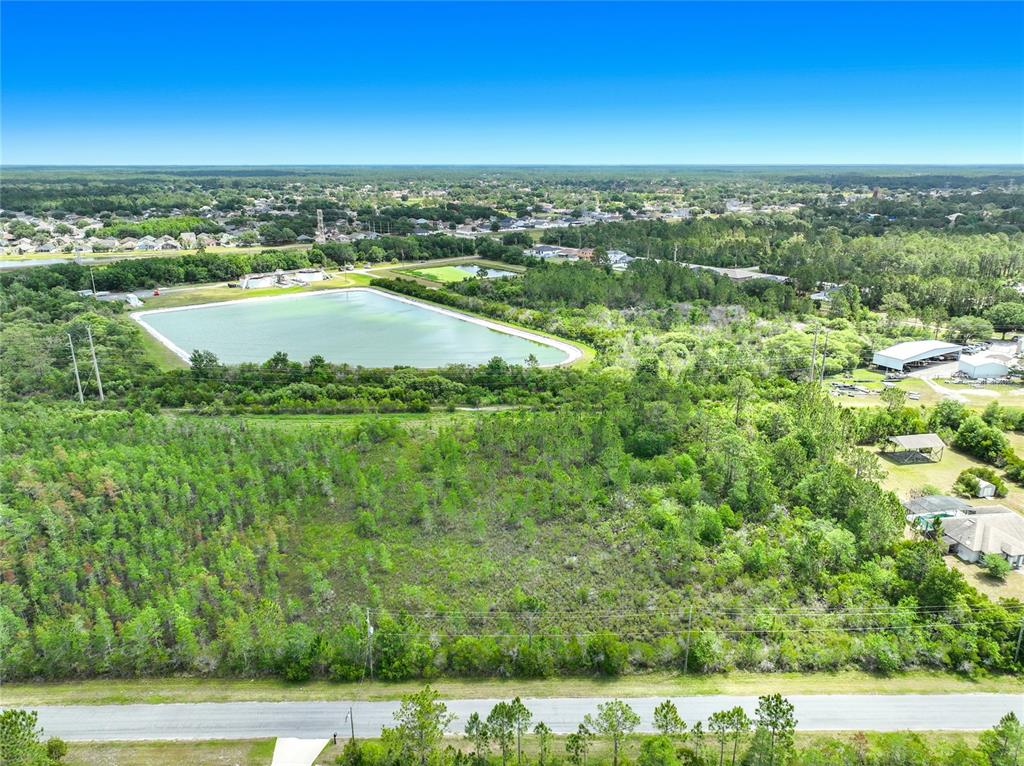 An aerial view shows a large, undeveloped wooded lot adjacent to a retention pond — 00 WEMBLEY AVENUE, ORLANDO, FL