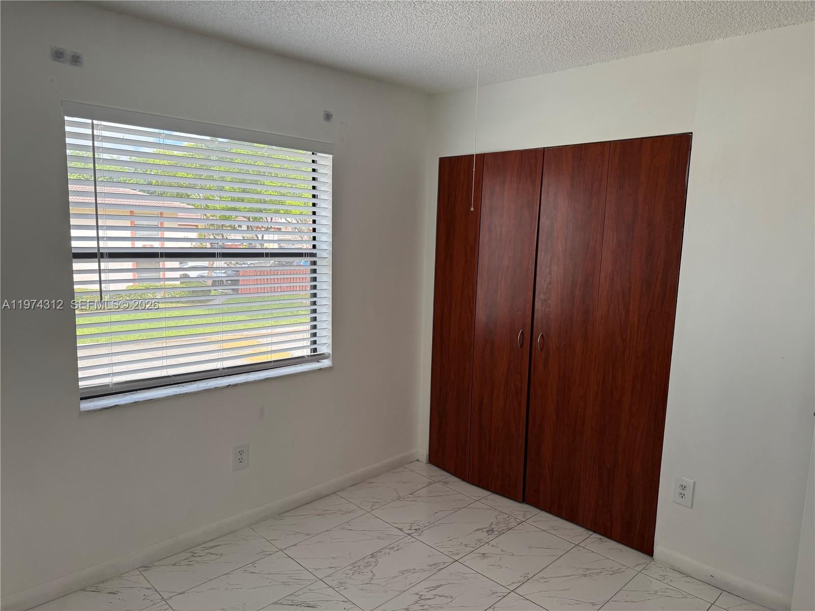 A room with white walls, white marble-look tile flooring, a window with blinds, and closets — 20825 NE 8th Ct # 19, Miami FL 33179, MIAMI, FL