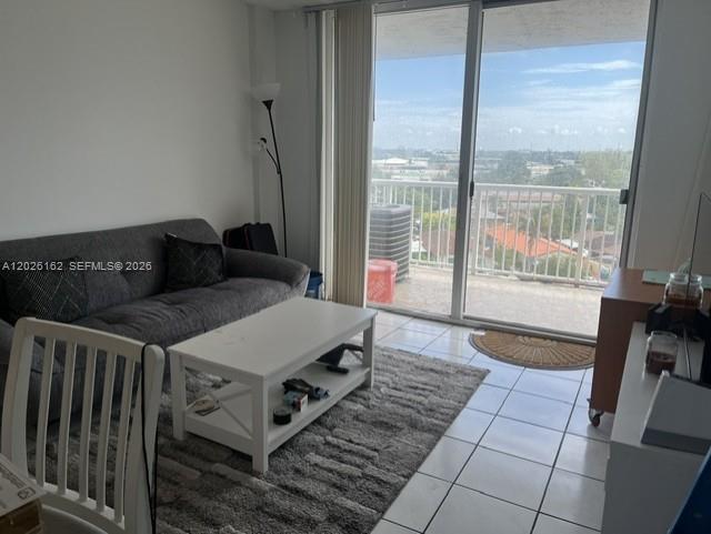 A living room features a gray sofa, white coffee table, and a balcony with city views — 1800 NW 24th Ave # 705, Miami FL 33125, MIAMI, FL