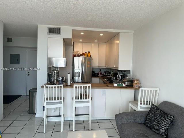 A kitchen with white cabinets and a breakfast bar sits adjacent to a living area — 1800 NW 24th Ave # 705, Miami FL 33125, MIAMI, FL