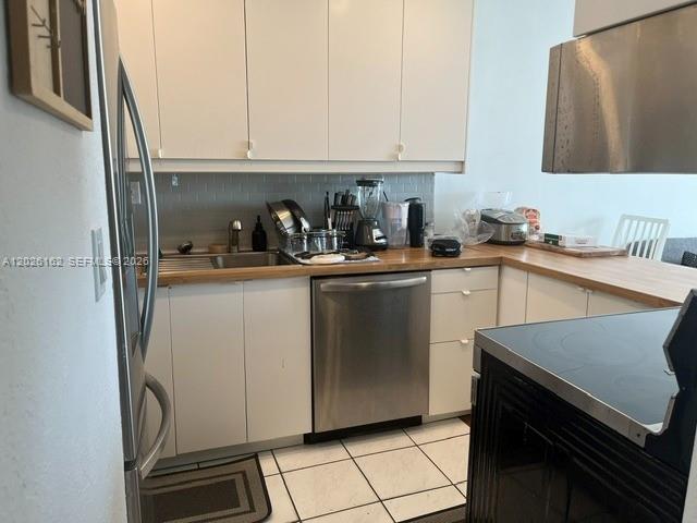 A kitchen features white cabinets, stainless steel appliances, and a light wood countertop — 1800 NW 24th Ave # 705, Miami FL 33125, MIAMI, FL