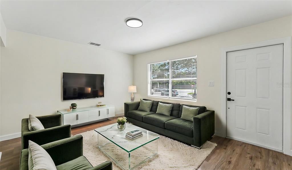 A living room features a dark green sofa, matching armchairs, a glass coffee table, and television — 621 HOLLINGSWORTH ROAD, LAKELAND, FL