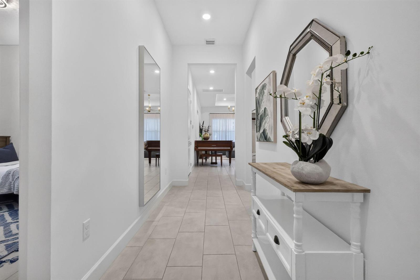 A bright hallway features light tile flooring, a console table, a mirror, and wall art — 4336 Matilda Court, Delray Beach FL 33445, DELRAY BEACH, FL