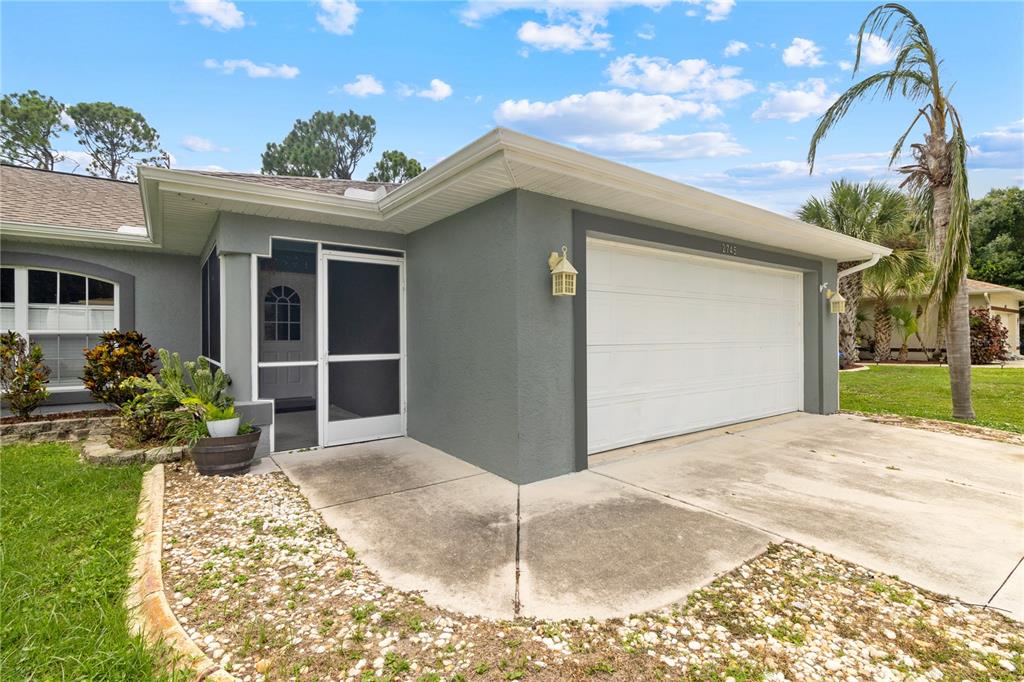 The exterior of a gray house features a two-car garage and a screened-in entryway — 2745 NELLIE LANE, NORTH PORT, FL