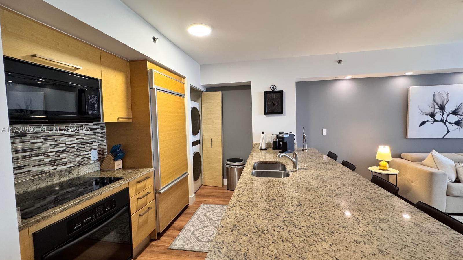 A kitchen features light wood cabinets, granite countertops, a large island, and a laundry closet — 1830 S Ocean Dr # 2209, Hallandale Beach FL 33009, HALLANDALE BEACH, FL