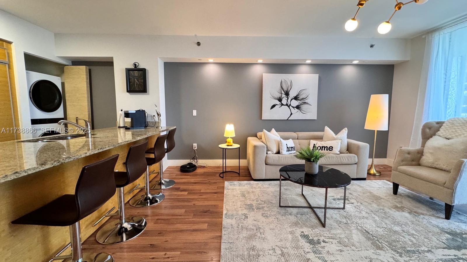 A living room with a gray accent wall, beige sofa, and a kitchen breakfast bar — 1830 S Ocean Dr # 2209, Hallandale Beach FL 33009, HALLANDALE BEACH, FL