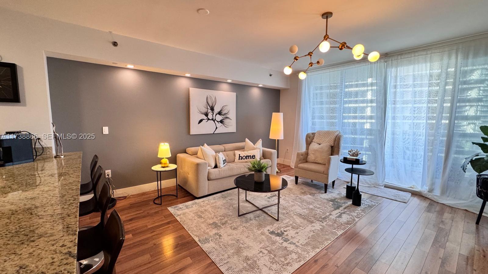A living room features a beige sofa, an armchair, a coffee table, and wood flooring — 1830 S Ocean Dr # 2209, Hallandale Beach FL 33009, HALLANDALE BEACH, FL
