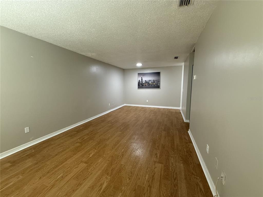 An empty room features light gray walls, wood-look flooring, and a framed city skyline print — 8534 CHANNELVIEW CIRCLE UNIT 8534, TAMPA, FL