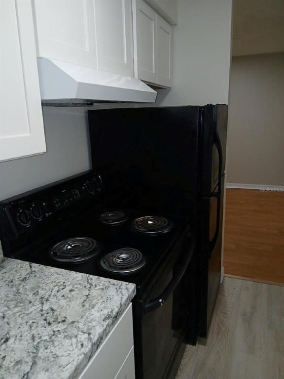 A kitchen features white shaker cabinets, granite countertops, a stainless steel sink, and a black stove — 8534 CHANNELVIEW CIRCLE UNIT 8534, TAMPA, FL