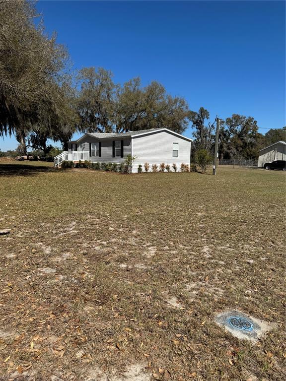 A light-colored manufactured home sits on a large, grassy lot with scattered trees — 5525 W EVANS STREET, COLEMAN, FL