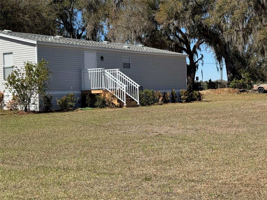 A light gray mobile home features a white door with a white railed wooden staircase — 5525 W EVANS STREET, COLEMAN, FL