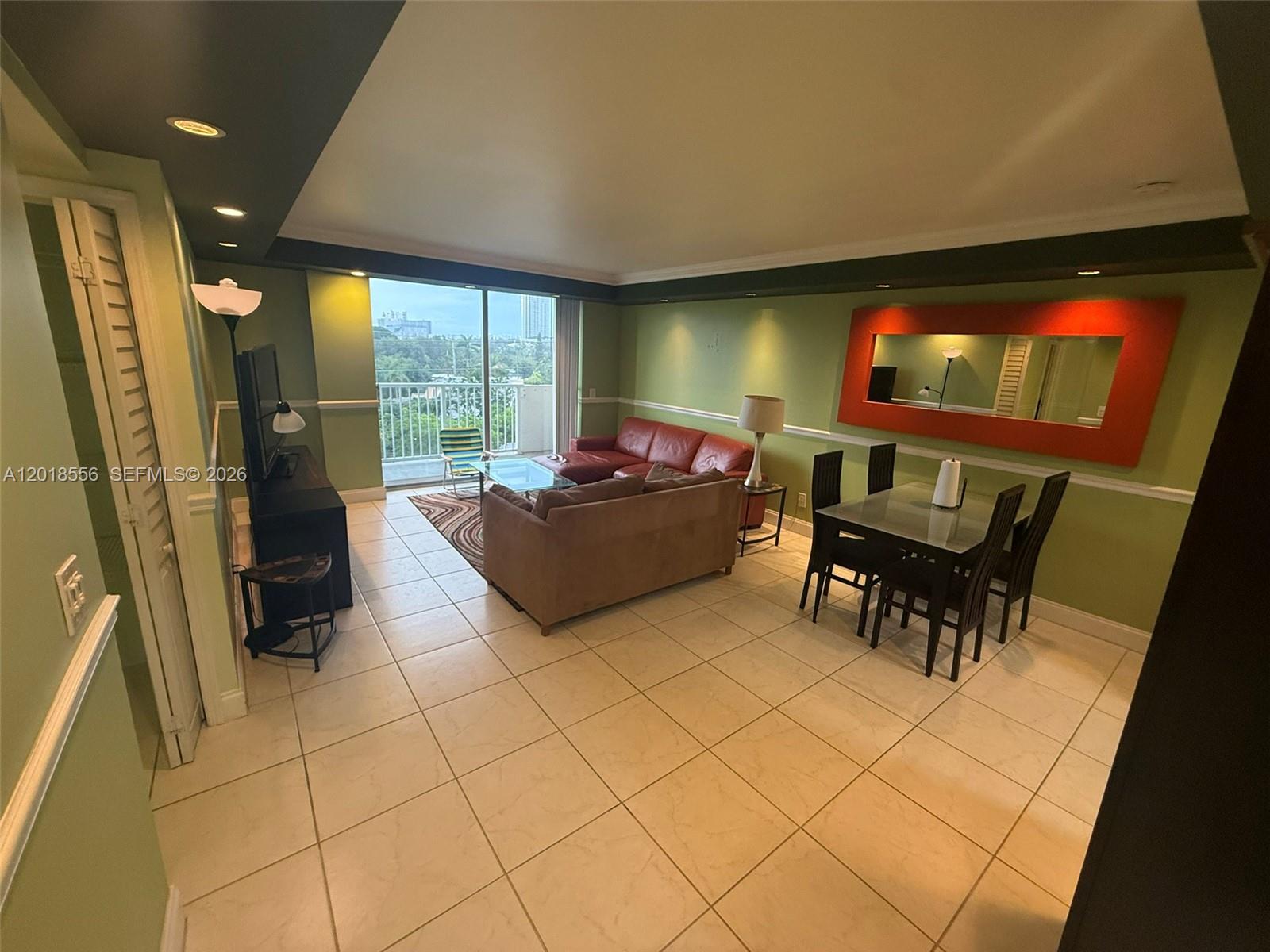 A living and dining area features tile floors, green walls, and a balcony with views — 2020 NE 135th St # 503, North Miami FL 33181, NORTH MIAMI, FL