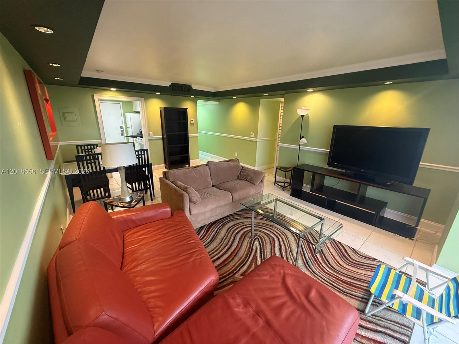 A living room features green walls, a red leather sofa, a brown couch, and tile flooring — 2020 NE 135th St # 503, North Miami FL 33181, NORTH MIAMI, FL
