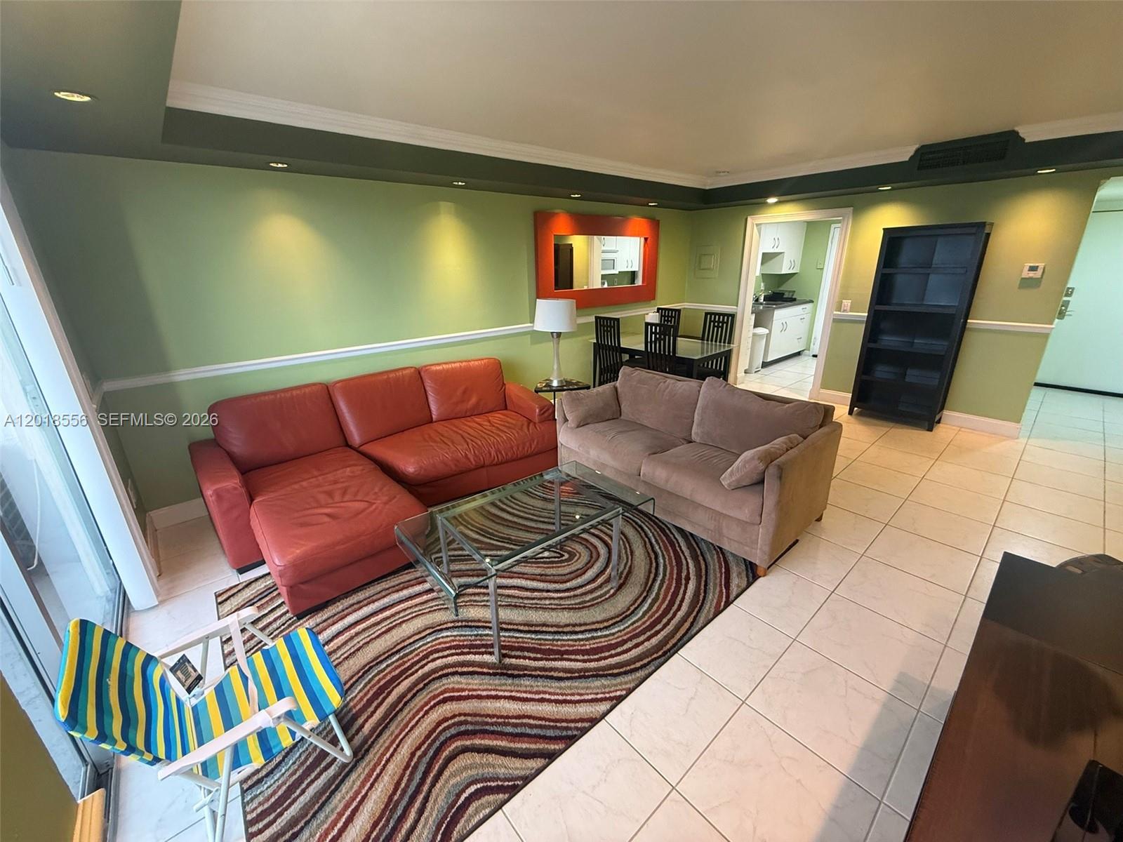 A living room features green walls, a red sectional, a brown sofa, and tile flooring — 2020 NE 135th St # 503, North Miami FL 33181, NORTH MIAMI, FL