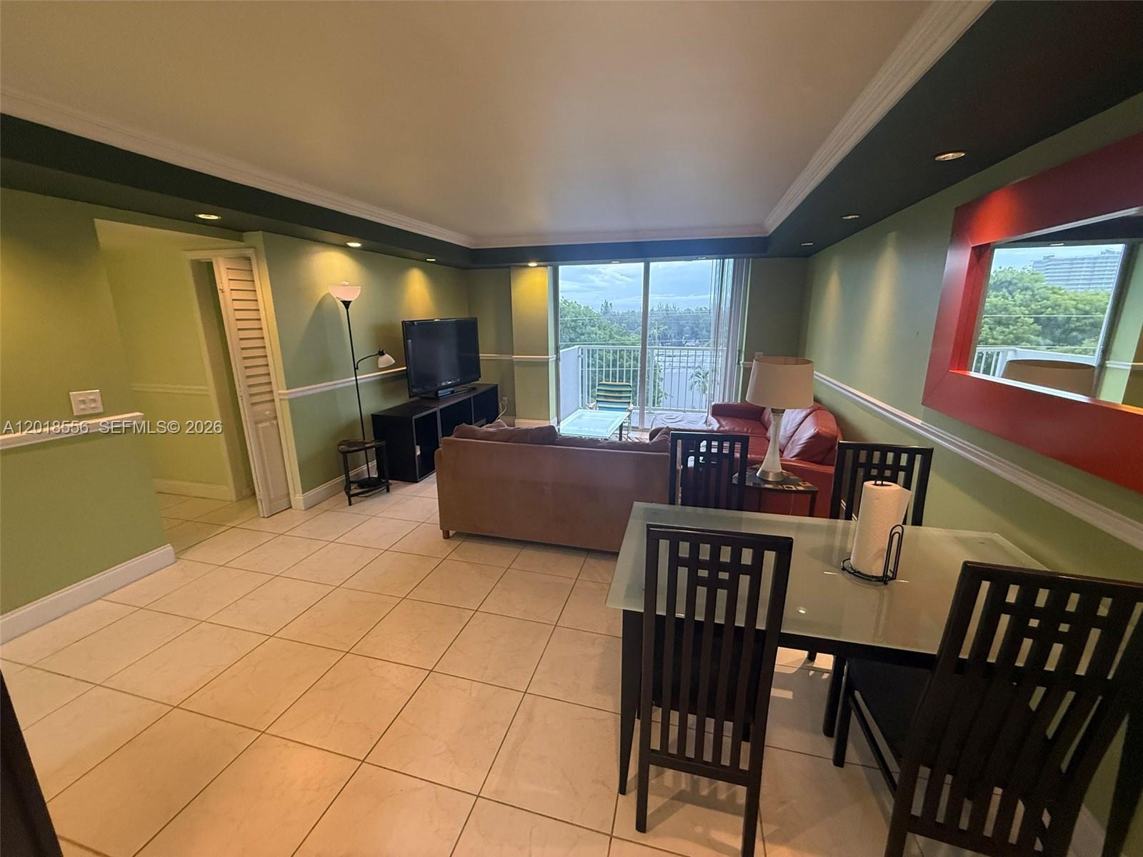 A living and dining area features light green walls, tile flooring, and a balcony view — 2020 NE 135th St # 503, North Miami FL 33181, NORTH MIAMI, FL