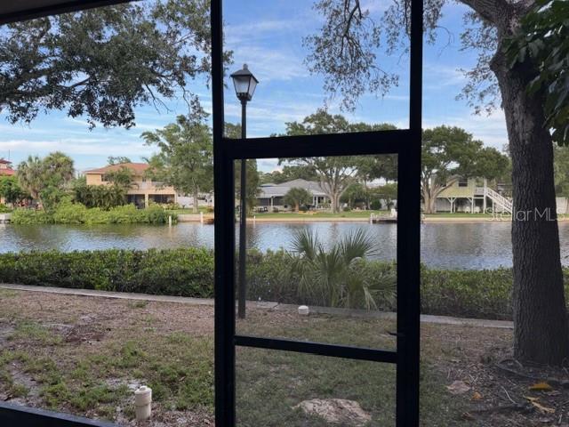 A view of a canal and neighboring houses seen through a screened-in porch — 9009 TUDOR DRIVE UNIT G106, TAMPA, FL