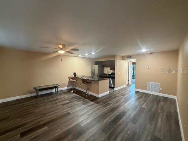 An open-concept living area features wood-look flooring, a kitchen island with bar stools, and cabinetry — 9009 TUDOR DRIVE UNIT G106, TAMPA, FL
