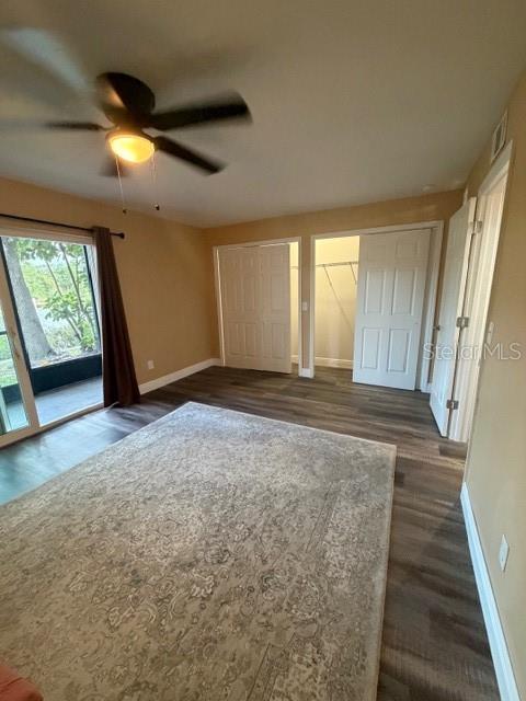 A bedroom features wood-look flooring, a ceiling fan, a large area rug, and closet doors — 9009 TUDOR DRIVE UNIT G106, TAMPA, FL
