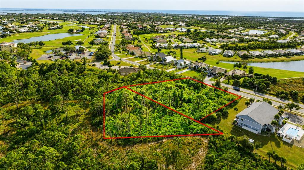 An aerial view shows a wooded, undeveloped lot outlined in red next to residential houses — 3989 CAPE HAZE DRIVE, ROTONDA WEST, FL