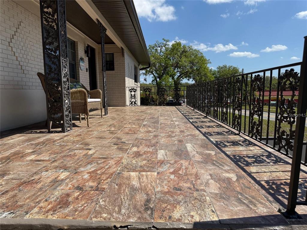 A covered porch features tiled flooring, decorative metal railings, and a wicker chair — 5418 RIVERHILLS DRIVE, TEMPLE TERRACE, FL