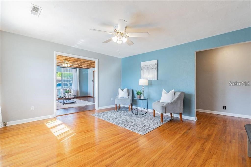 A living room features hardwood floors, a blue accent wall, and two gray armchairs — 5418 RIVERHILLS DRIVE, TEMPLE TERRACE, FL