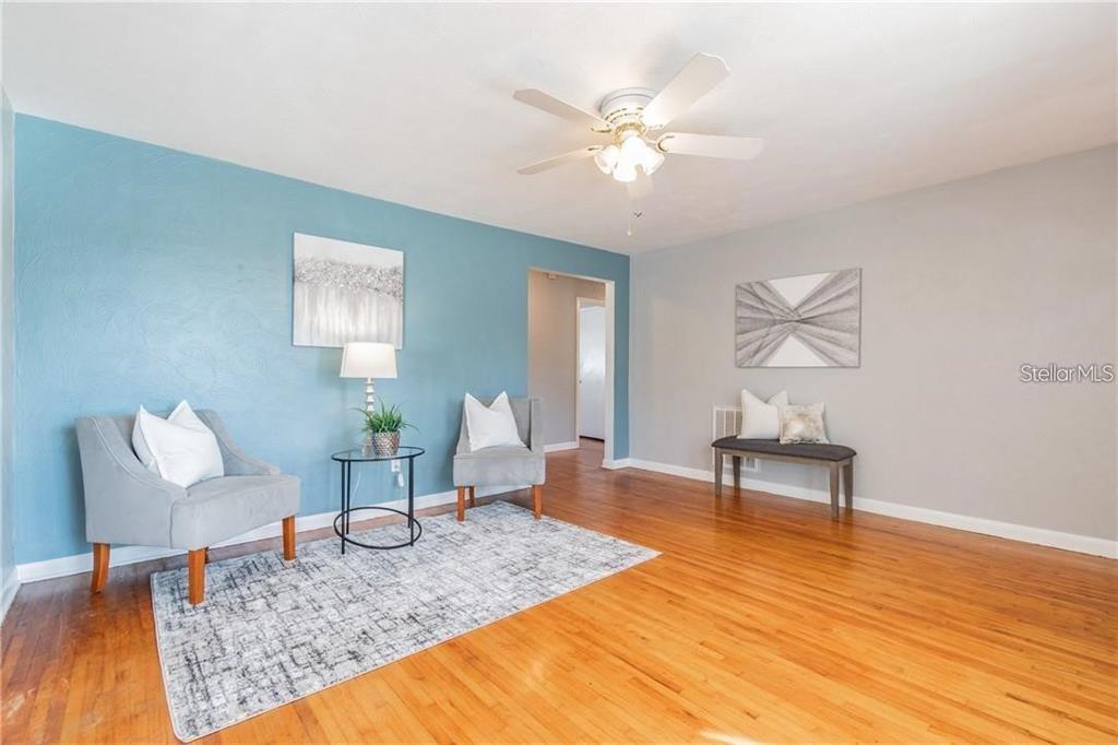 A living room features hardwood floors, a blue accent wall, and a ceiling fan — 5418 RIVERHILLS DRIVE, TEMPLE TERRACE, FL