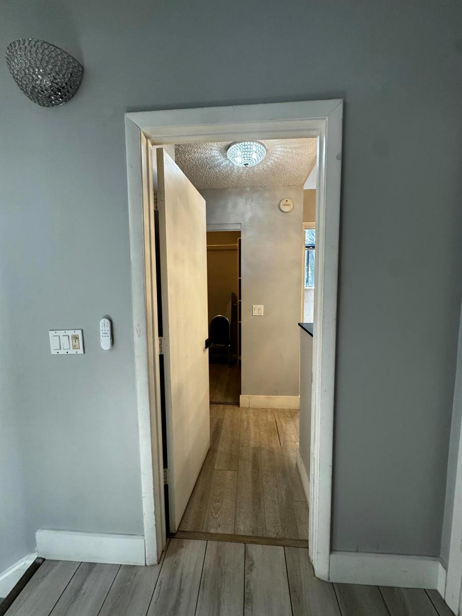 A view through a doorway shows a hallway with light wood-look flooring and gray walls — 1908 Players Place, North Lauderdale FL 33068, NORTH LAUDERDALE, FL
