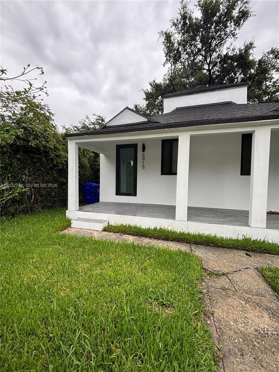 A white house with a covered front porch, dark trim, and a gray tiled floor — 6915 NW 4th Ct # 6915, Miami FL 33150, MIAMI, FL
