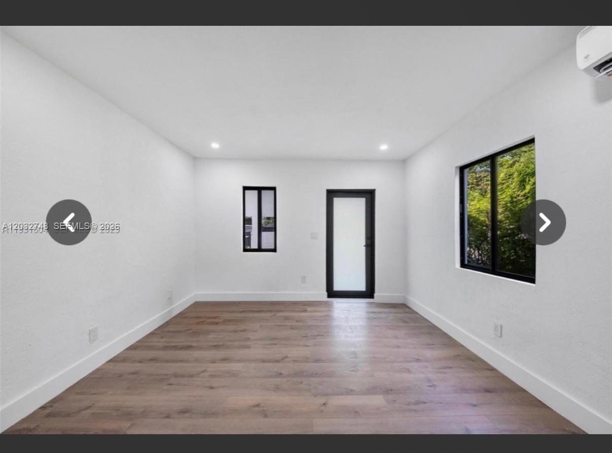 An empty room with white walls, wood-look flooring, a glass door, and two windows — 6915 NW 4th Ct # 6915, Miami FL 33150, MIAMI, FL