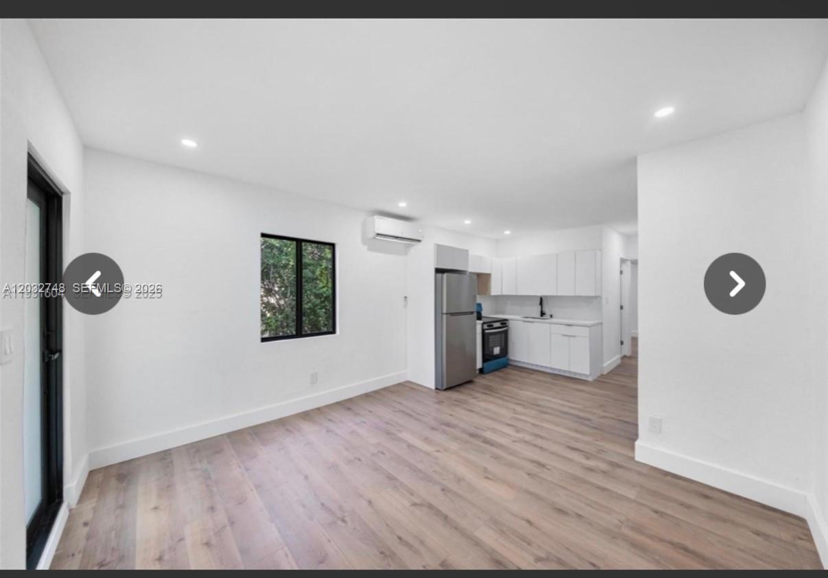 A bright, open-concept living area features white walls, light wood-look flooring, and a modern kitchen — 6915 NW 4th Ct # 6915, Miami FL 33150, MIAMI, FL
