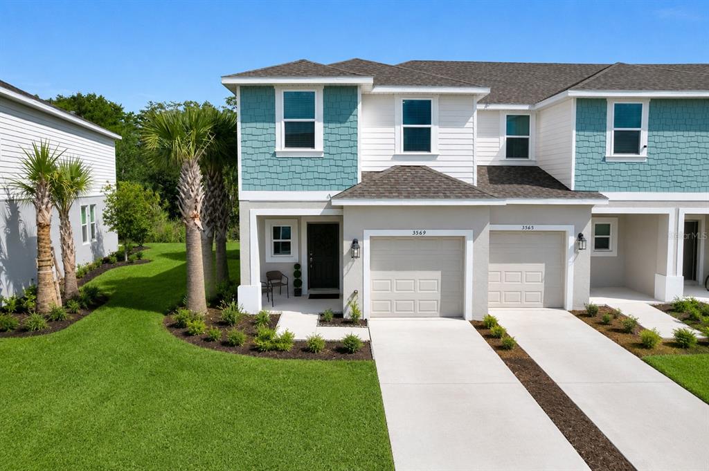 A two-story townhouse with a teal shingle facade, a garage, and a small front porch — 3569 MAYFAIR STREET, KISSIMMEE, FL