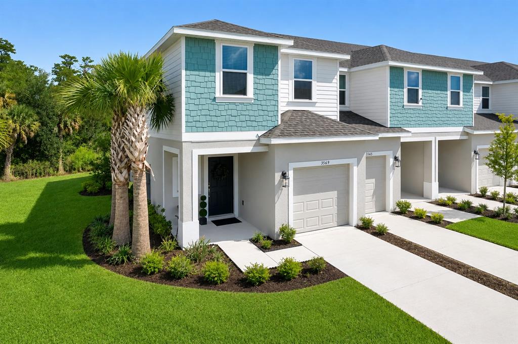 An exterior view of a two-story townhouse with teal shingle siding and a concrete driveway — 3569 MAYFAIR STREET, KISSIMMEE, FL