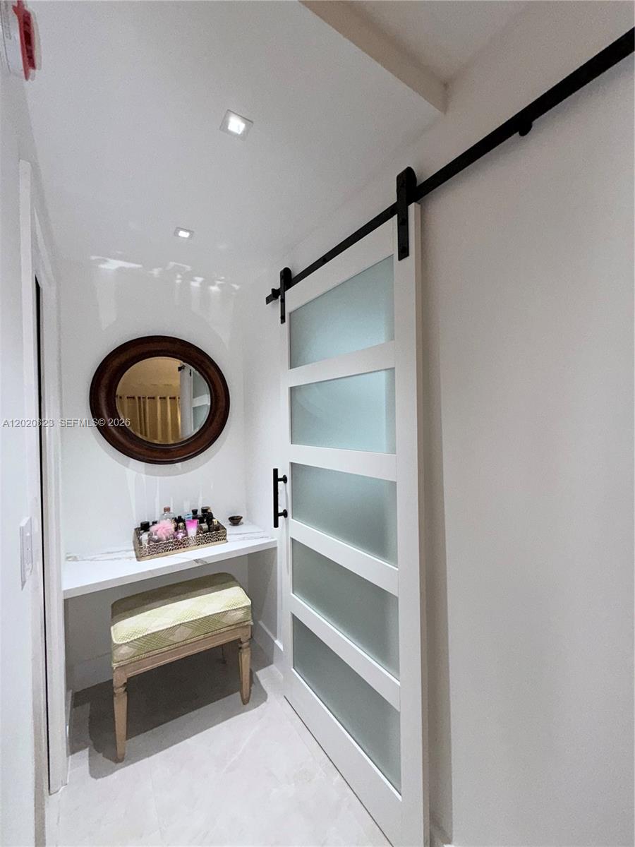 A small vanity area features a round mirror, a stool, and a frosted sliding door — 605 Oaks Dr # 307, Pompano Beach FL 33069, POMPANO BEACH, FL