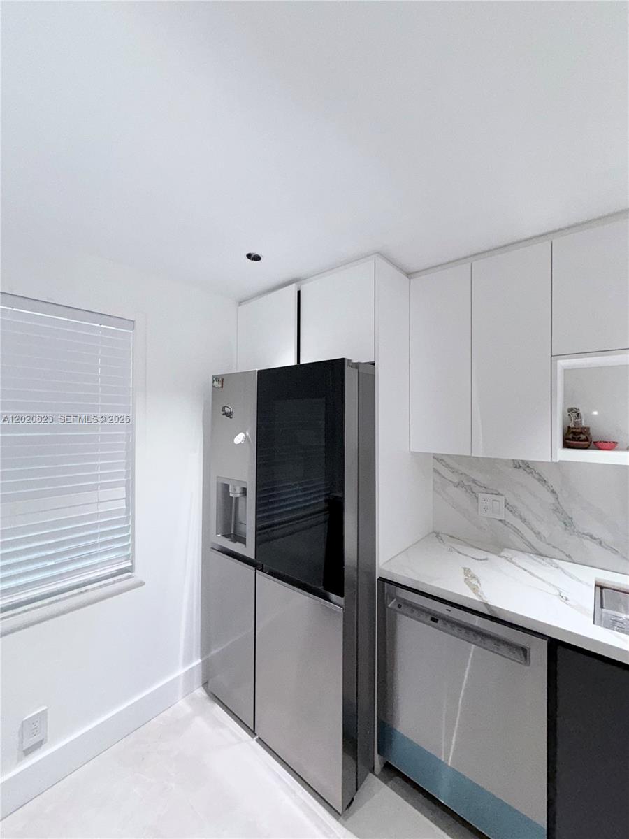 A modern kitchen features white cabinets, a stainless steel refrigerator, and marble-patterned countertops — 605 Oaks Dr # 307, Pompano Beach FL 33069, POMPANO BEACH, FL
