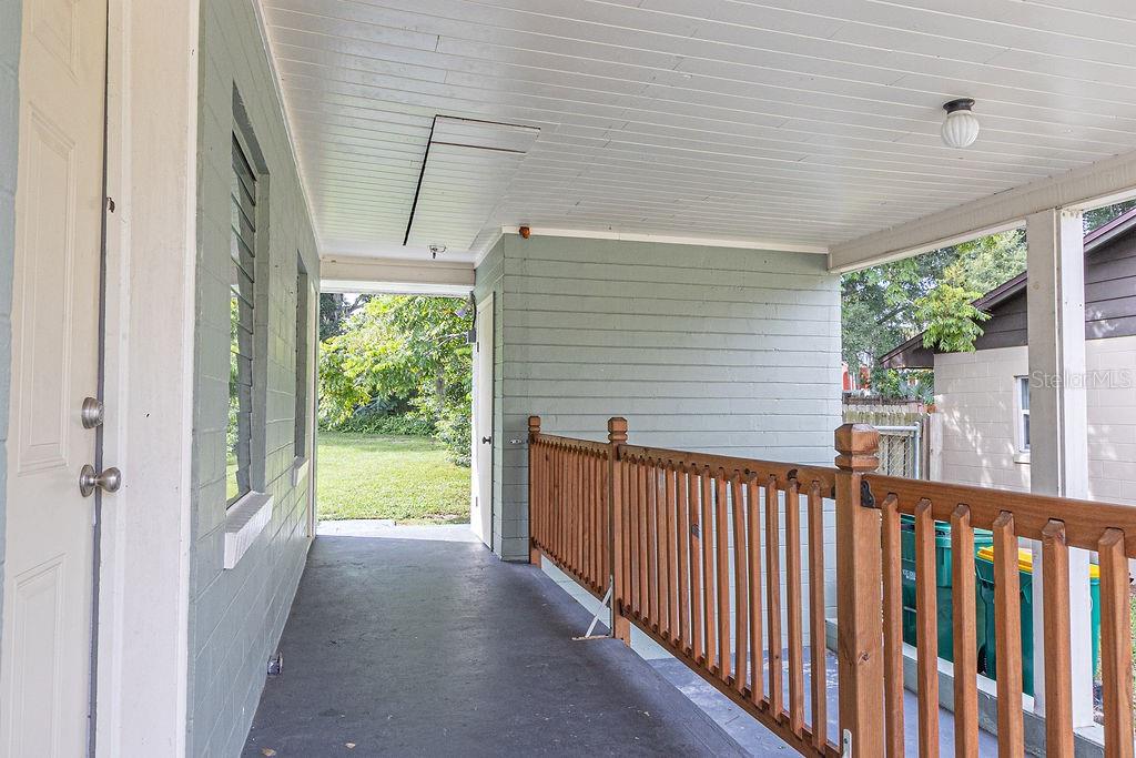 A covered porch features light green siding, a wooden railing, and a concrete floor — 630 E INDIANA AVENUE, DELAND, FL