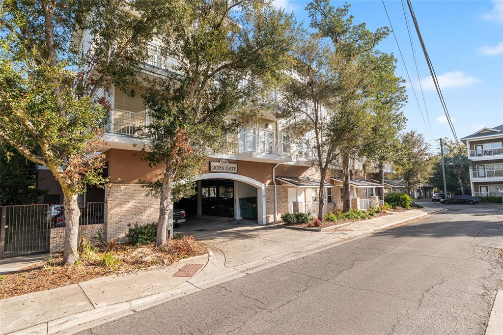 A multi-story apartment building with a covered parking entrance labeled Lions Gate — 1500 NW 4TH AVENUE UNIT 203, GAINESVILLE, FL