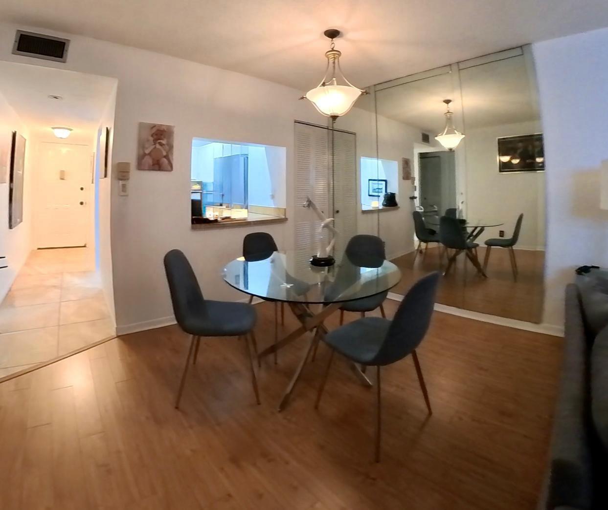 A dining area features a glass-topped table, four gray chairs, and a large mirrored wall — 2161 W Woolbright Road # m202, Boynton Beach FL 33426, BOYNTON BEACH, FL