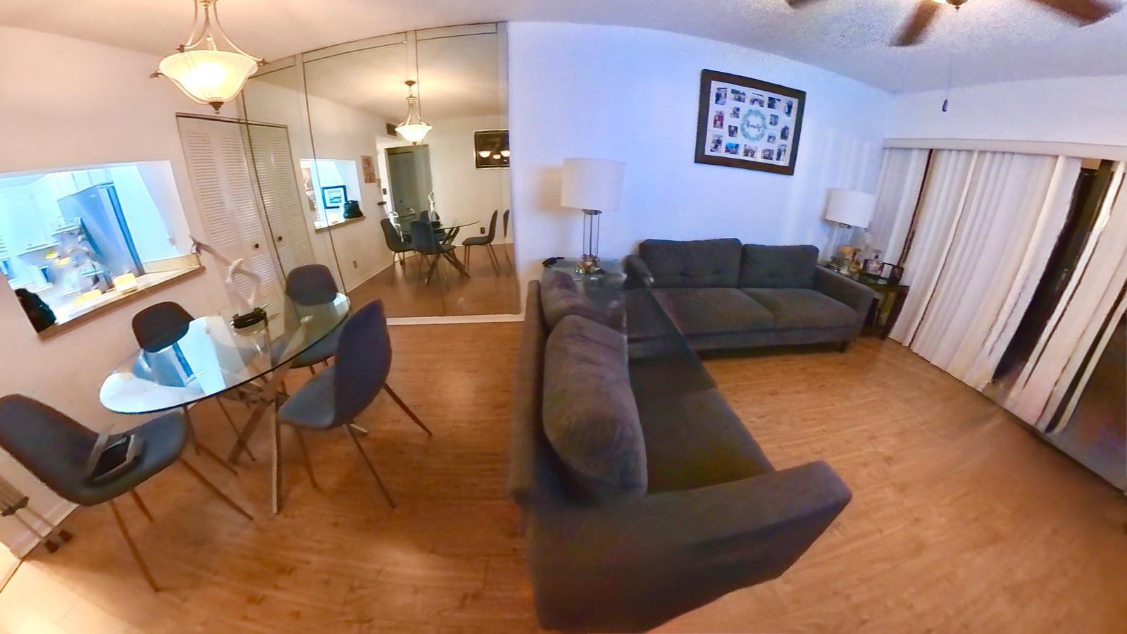 A living room and dining area with wood-look flooring, a glass table, and gray sofas — 2161 W Woolbright Road # m202, Boynton Beach FL 33426, BOYNTON BEACH, FL