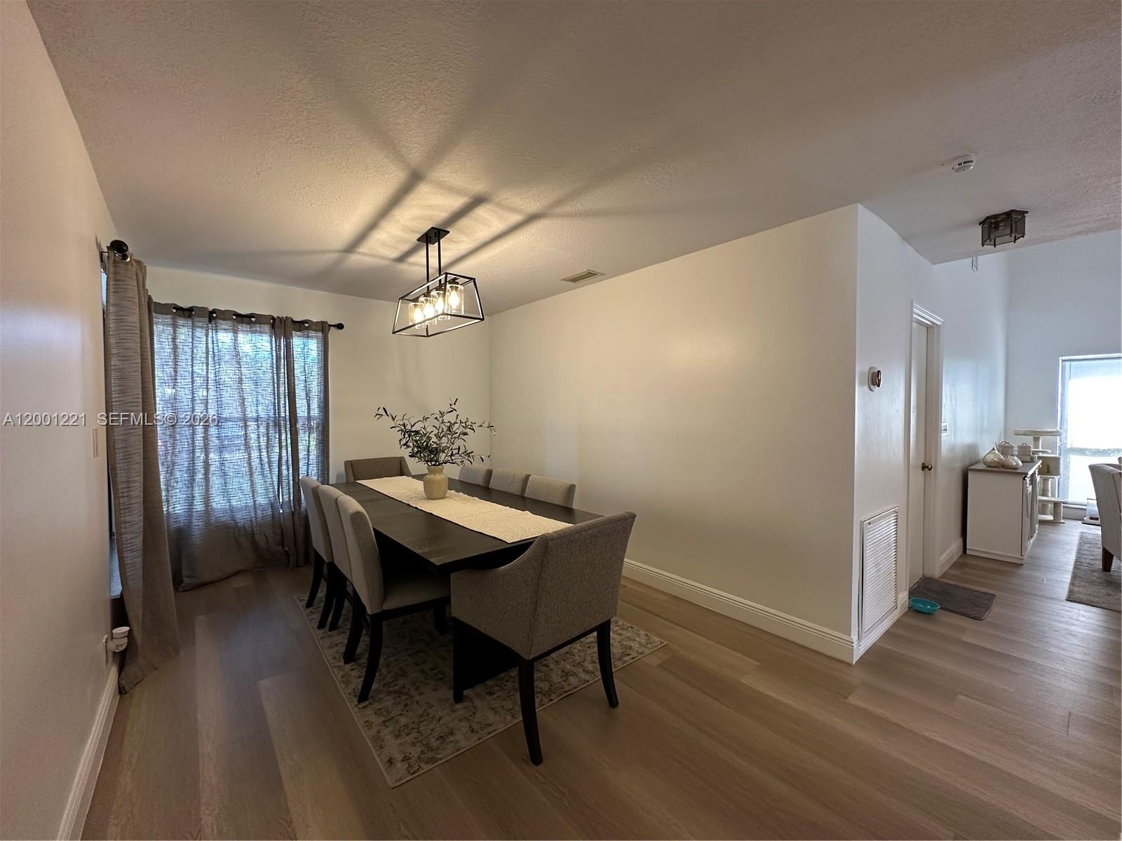 A dining room features a dark table, gray upholstered chairs, and a modern light fixture — 7003 NW 40th Pl, Coral Springs FL 33065, CORAL SPRINGS, FL