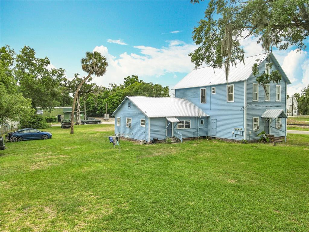 A blue two-story house with a metal roof sits on a large grassy lot — 161 W 2ND AVENUE, PIERSON, FL