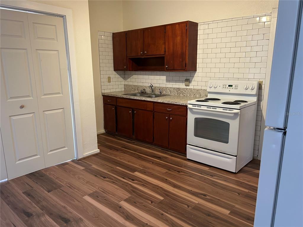 A kitchen features wood cabinets, a white stove, a granite countertop, and white subway tile — 161 W 2ND AVENUE, PIERSON, FL