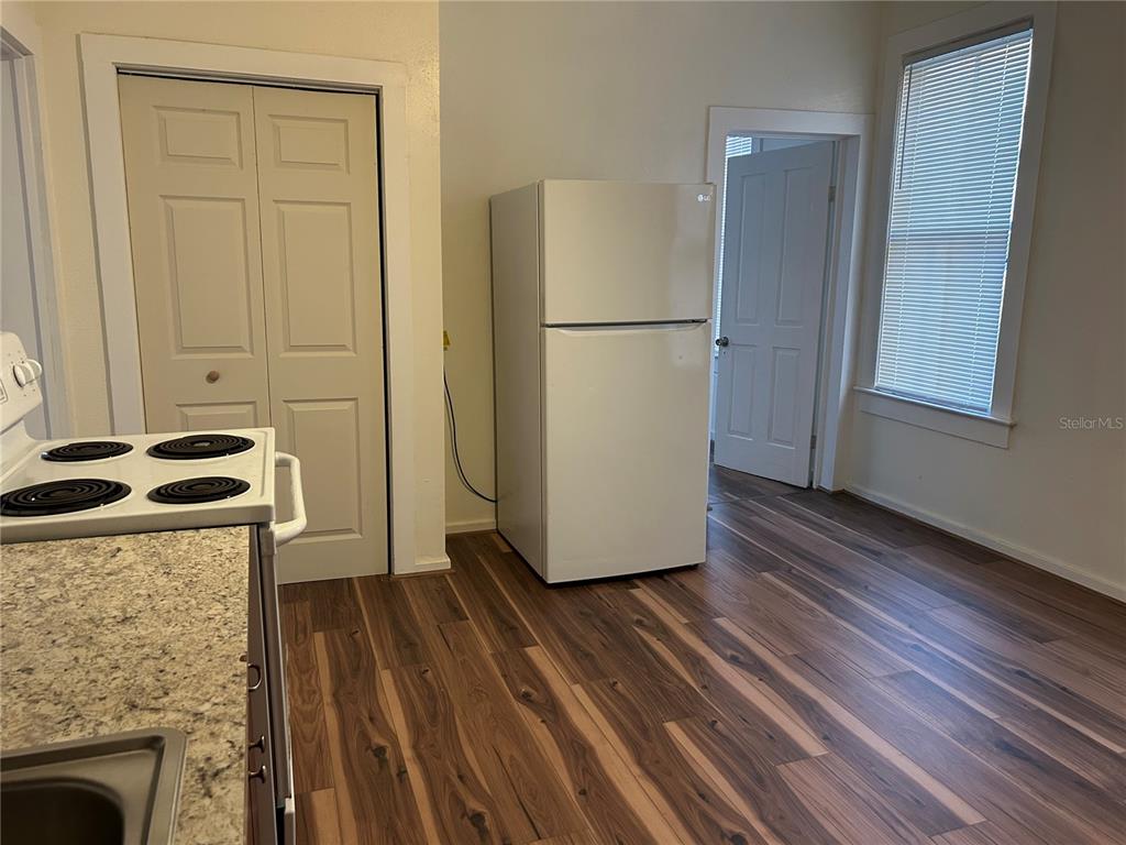 A kitchen features a white refrigerator, a stove, wood-look flooring, and a window with blinds — 161 W 2ND AVENUE, PIERSON, FL